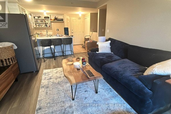 Living room with dark blue sectional sofa, live edge coffee table, and area rug. - 208 - 625 St David Street S, Centre Wellington