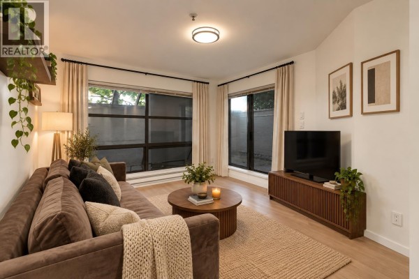 Living room with light wood floors, white walls, a brown sofa, and a small round table with stools. - 208 1106 Pacific Street, Vancouver