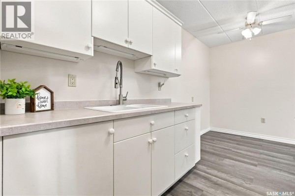 Close-up of apartment kitchen sink, countertops, and white cabinetry. - 208 2830 Gordon Road, Regina