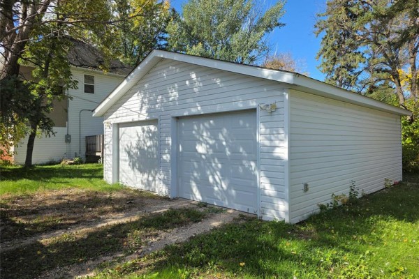 White two-car garage with vinyl siding and two garage doors, situated on a grassy lawn. - 208 2nd Street, Oakville