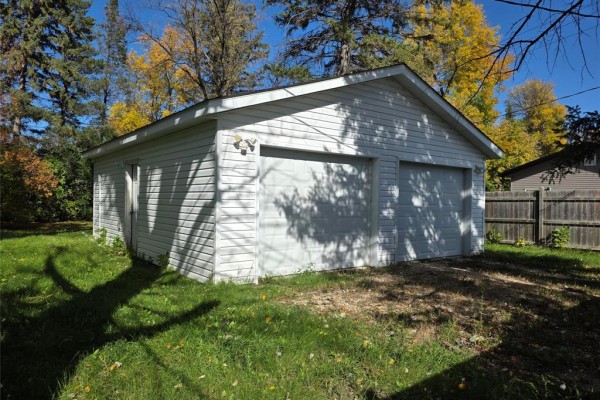 Side view of a white two-car garage with white siding and two white garage doors. - 208 2nd Street, Oakville
