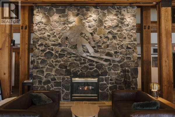 Lounge area featuring a stone wall with a skier sculpture and a fireplace, with leather sofas. - 208 4200 Whistler Way, Whistler