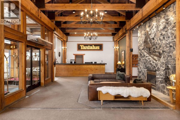 Reception area with wooden accents, a stone wall, and a chandelier, featuring a seating area. - 208 4200 Whistler Way, Whistler