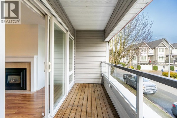 Empty room with wood floors, white walls, a window, and a standing lamp. - 208 4989 47 Avenue, Ladner