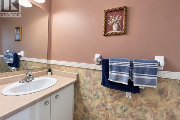 Bathroom vanity with white sink, silver faucet, and towels hanging on a rack against a pink wall. - 208 Activa Avenue, Kitchener