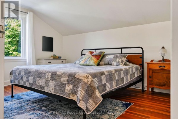 Bedroom with metal bed, quilt, and hardwood floors - 208 Albert Street Cobourg