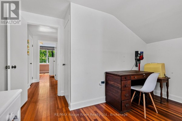 Hallway with hardwood floors, desk, chair, vacuum cleaner, and sewing machine cover - 208 Albert Street Cobourg
