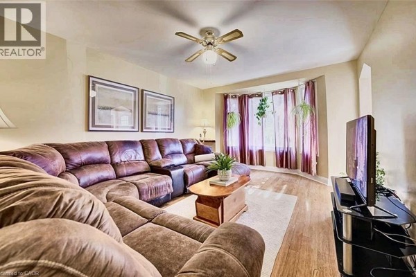 Living room with a large brown sectional sofa, coffee table, and television. - 208 Arnold Street, Kitchener
