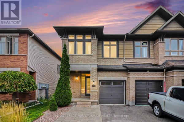 Exterior front view of a stone and wood townhouse with an attached garage at dusk. - 208 Butterfly Walk, Ottawa