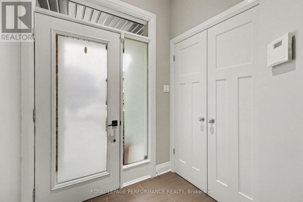 Interior entryway with a glass door, tiled floor, and two white closets. - 208 Butterfly Walk, Ottawa