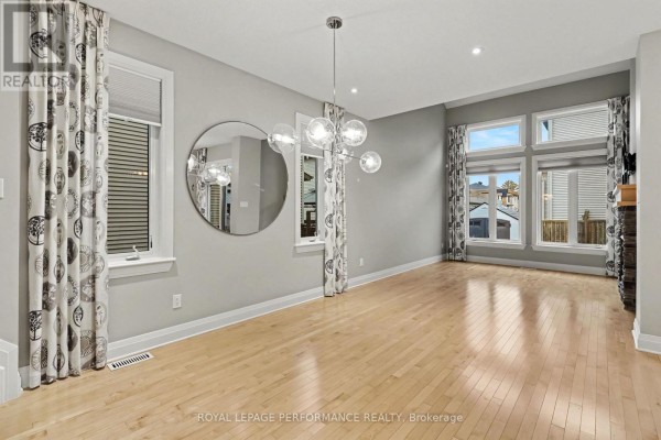 Open concept dining and living room with wood floors and large windows. - 208 Butterfly Walk, Ottawa