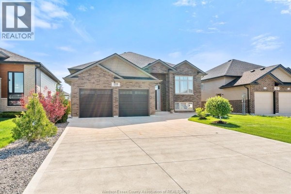 Exterior view of a large brick house with a two-car garage and concrete driveway. - 208 Clarke, Amherstburg