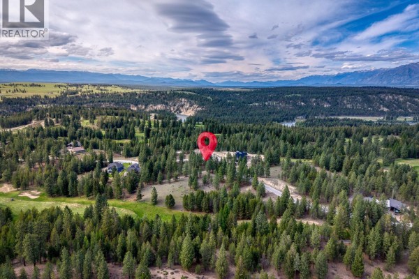 Aerial view of a lot with a red marker, surrounded by trees, golf course, and mountains. - 208 Corral Boulevard Lot# 30, Cranbrook
