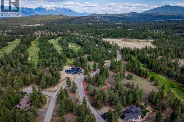 Aerial view of a property lot with a red marker, showing neighboring houses and distant mountains. - 208 Corral Boulevard Lot# 30, Cranbrook