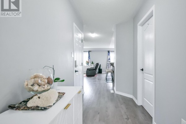 Hallway with light grey walls, wood-look laminate flooring, and doors leading to other rooms. - 208 Diana Drive, Orillia