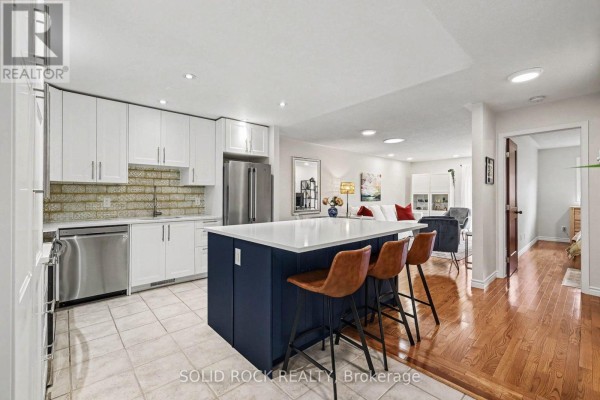 Modern kitchen with white cabinets, stainless steel appliances, and a blue island with bar stools. - 208 Jamieson Street, Mississippi Mills