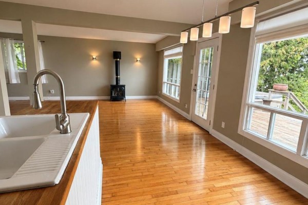 Living room with hardwood floors, a wood stove, and large windows overlooking the water. - 208 Kempview Lane, Barrie