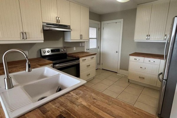 Kitchen with white cabinets, wood countertops, a double sink, and stainless steel appliances. - 208 Kempview Lane, Barrie