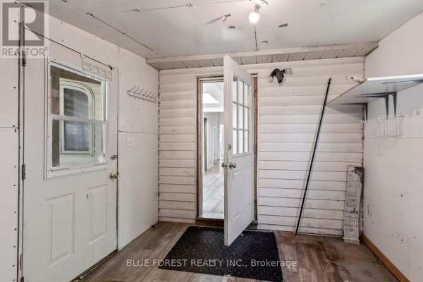 Interior view of a mudroom with two doors, wood-paneled walls, and vinyl flooring. - 208 Maitland Street, London East