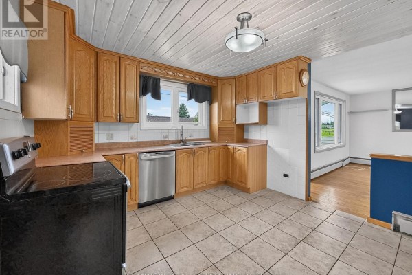 Kitchen with oak cabinets, stainless steel appliances, and a view into the adjacent dining area. - 208 Marion Street, Iroquois Falls