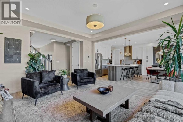 Living room with a fireplace, dark velvet armchairs, and a view of the staircase. - 208 Osborne Green Sw, Airdrie