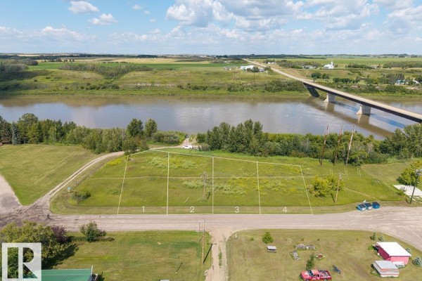 Aerial view of grassy property with river and bridge in background. - 208 River St, Duvernay