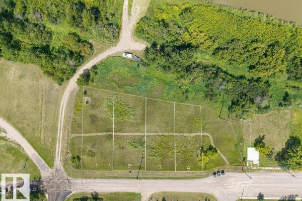 Aerial view of empty lot with gravel driveway and river in distance. - 208 River St, Duvernay