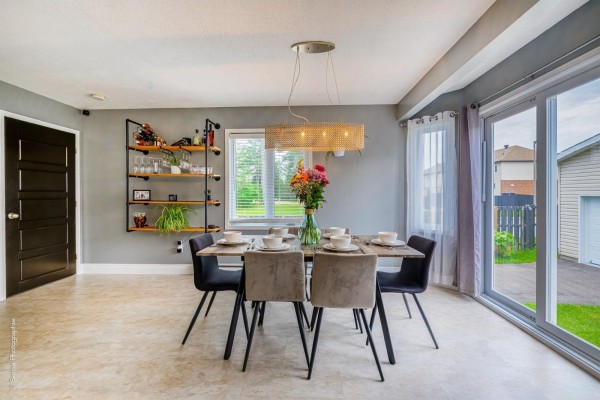 Open-concept living room and dining area with a grey sectional, dining table, and kitchen visible in the background. - 208 Rue Paul-laframboise, Gatineau
