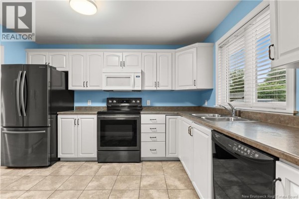 Kitchen with white cabinets, stainless steel appliances, beige countertops, and blue walls. - 208 Virginia Unit# 116, Dieppe