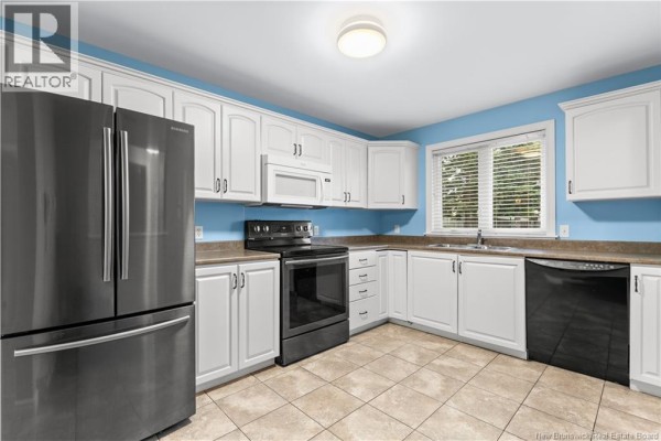 Corner view of kitchen featuring white cabinets, stainless steel refrigerator, and beige tile flooring. - 208 Virginia Unit# 116, Dieppe