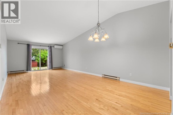 Spacious living room with vaulted ceiling, hardwood floors, and sliding glass door. - 208 Virginia Unit# 116, Dieppe