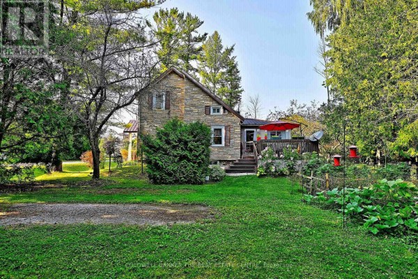 Front view of the stone cottage with a small porch, front door, and path. - 20805 Brock Road, Brock
