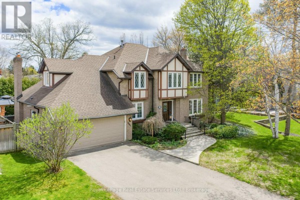 Aerial view of a large brick house with a driveway, garage, and mature trees. - 2082 Mississauga Road, Mississauga