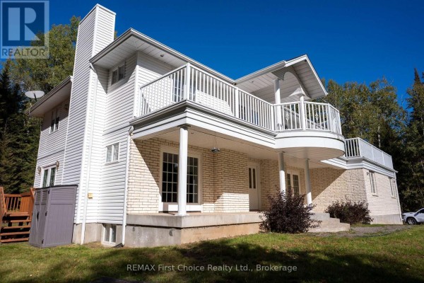 Close-up of the white house's entrance with French doors, columns, and a curved balcony above. - 2086 Granite Road, Thunder Bay