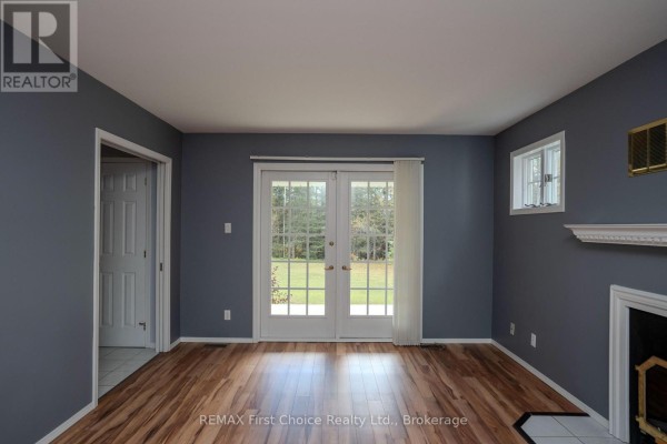 Living room with dark grey walls, wood floors, French doors, and a fireplace. - 2086 Granite Road, Thunder Bay