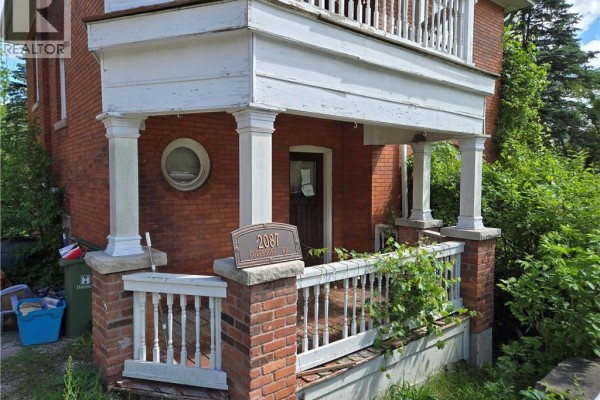 Close-up of the front porch with brick pillars, white railings, and address plaque. - 2087 Governors Road, Copetown