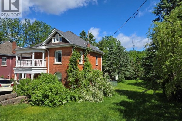 Side view of a red brick house showing large windows and surrounding green trees. - 2087 Governors Road, Copetown