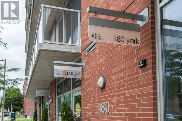 Close-up exterior view of retail storefronts and signage on a brick building. - 209 - 180 York Street, Ottawa
