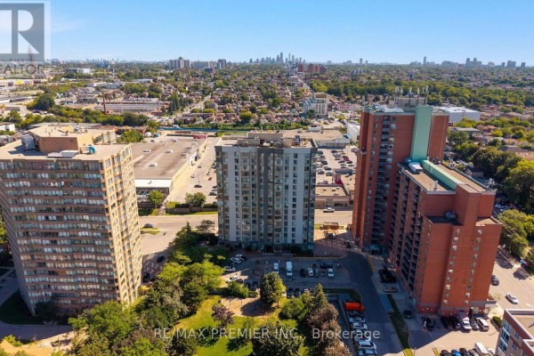 Aerial view of several apartment buildings, parking lots, and greenery under a clear blue sky. - 209 - 2470 Eglinton Avenue W, Toronto
