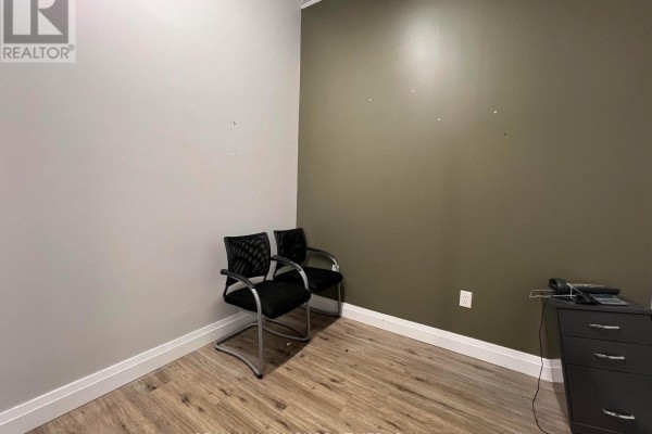 Boardroom with dark wood floor, large window overlooking a parking lot, and a grey stone accent wall. - 209 - 3485 Rebecca Street, Oakville