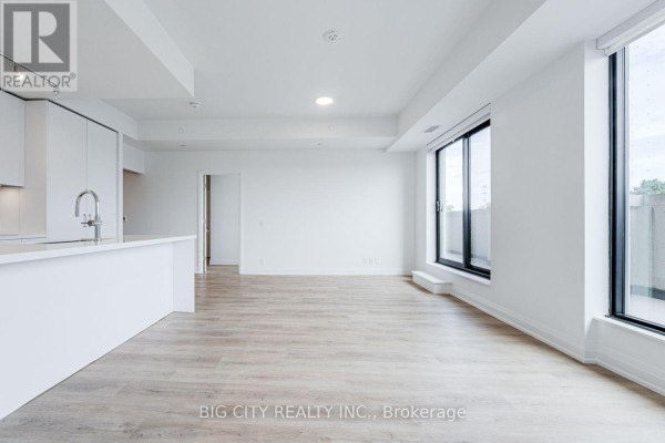 Bright open concept living and kitchen area with large windows and light flooring. - 209 - 36 Brentcliffe Road, Toronto