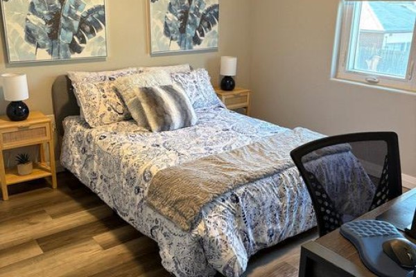 Bedroom with queen-size bed, patterned bedding, and a desk. - 6479 Montrose Road, Niagara Falls