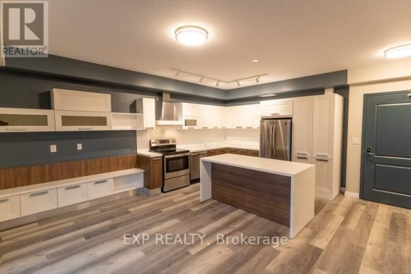 Open-concept living area with kitchen, dining island, and balcony access. - 6479 Montrose Road, Niagara Falls