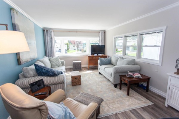 Living room with two sofas, an armchair, coffee tables, and a large rug. - 209 1840 160 Street, Surrey