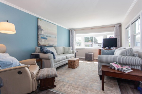 Living room with a fireplace, two sofas, armchair, and a view of the kitchen. - 209 1840 160 Street, Surrey
