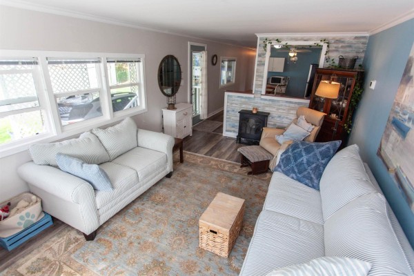 Living room with two sofas, armchair, ottoman, and a view of the kitchen area. - 209 1840 160 Street, Surrey
