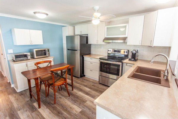 Kitchen with stainless steel appliances, a double sink, and a small wooden dining table. - 209 1840 160 Street, Surrey