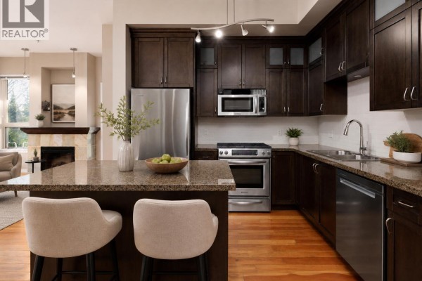 Kitchen with dark wood cabinets, granite island, stainless steel appliances, and pendant lighting. - 209 240 Salter Street, New Westminster