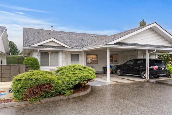 Front exterior of a white duplex with a covered carport, driveway, and landscaping. - 209 7610 Evans Road, Sardis West Vedder, Chilliwack