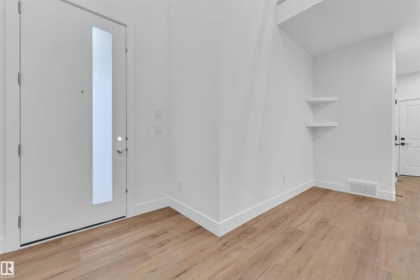 Bright entryway with high ceilings, white walls, and wooden flooring. - 209 Basin Co, Leduc
